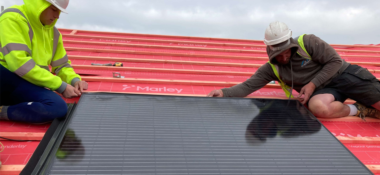 Two roofers installing solar panels onto a marley battened roof